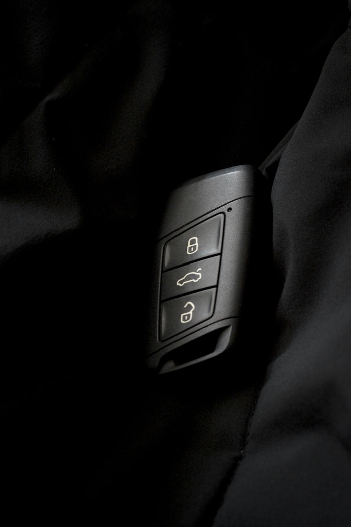 Detailed photo of a car key fob showing lock and unlock buttons on a dark surface.