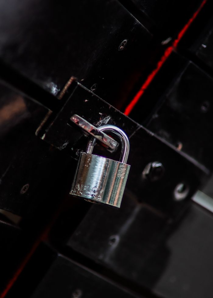 Close-up view of a metal padlock securing a dark door latch, symbolizing safety and protection.